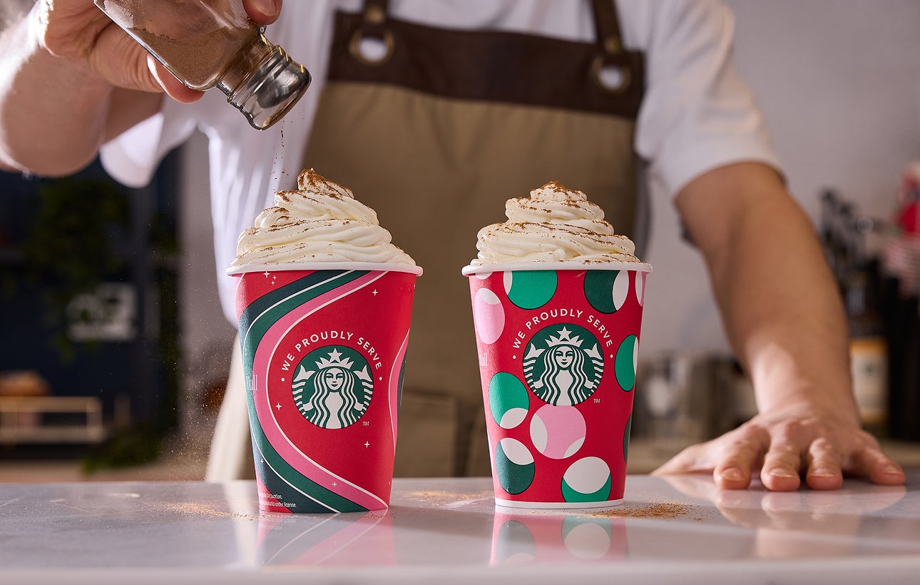 Deux boissons frappées Frappuccino® servies dans des tasses festives We Proudly Serve Starbucks, l’une d’elles étant saupoudr