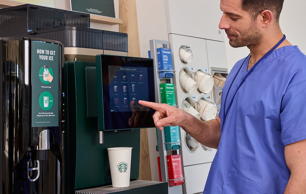Un professionnel de santé choisissant une boisson à la machine à café en libre-service We Proudly Serve Starbucks