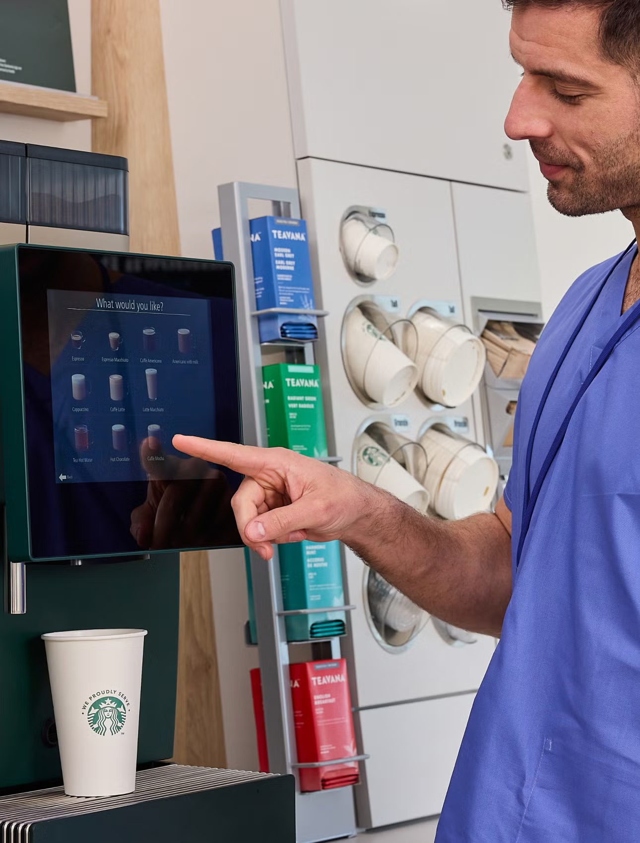 Un professionnel de santé choisissant une boisson à la machine à café en libre-service We Proudly Serve Starbucks
