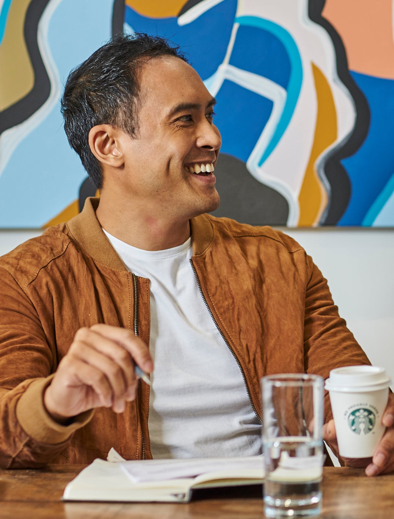 Des hommes assis à une table tenant un café We Proudly Serve Starbucks