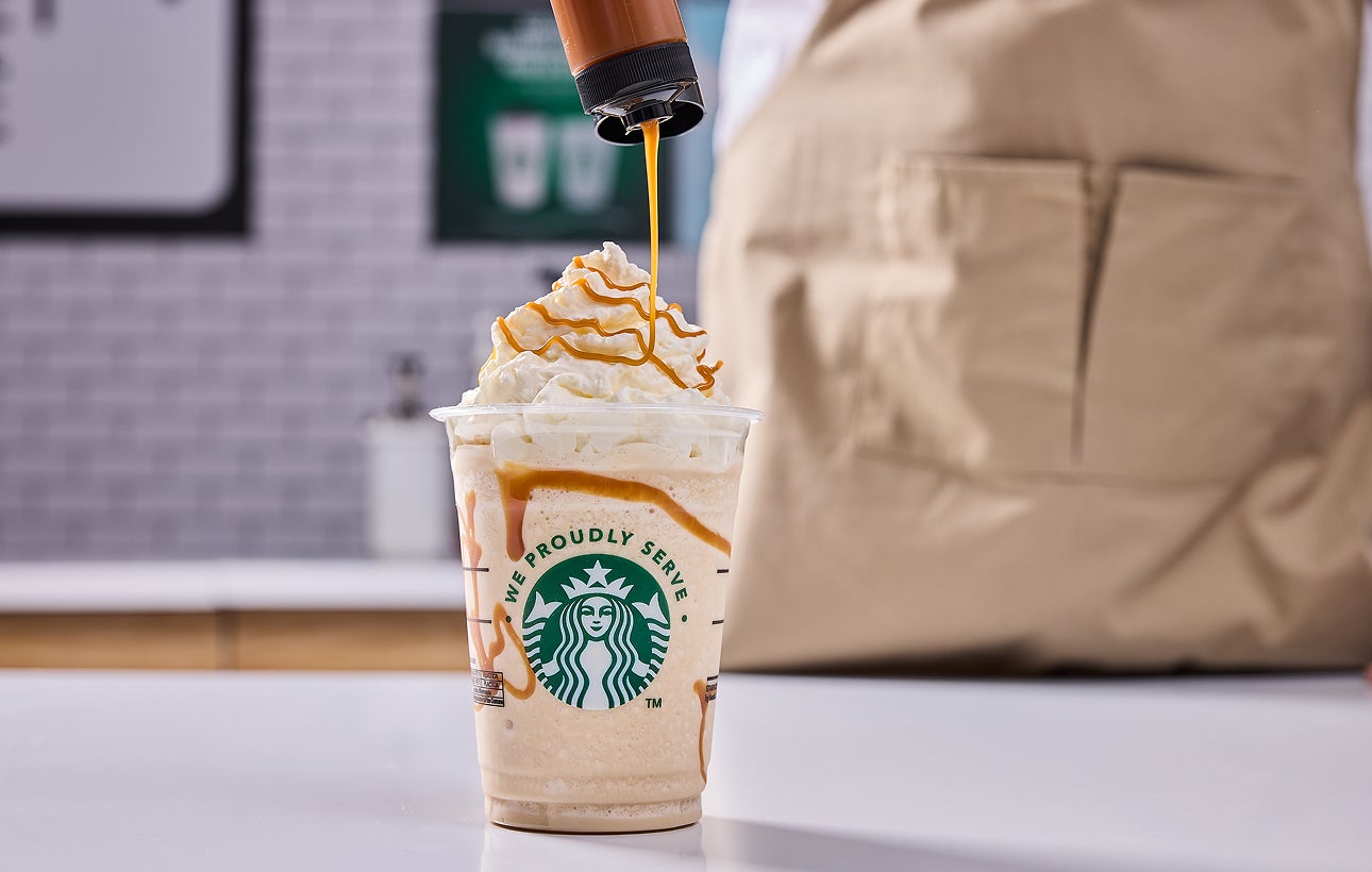 Une boisson frappée Starbucks nappée de crème fouettée, avec un filet de caramel ajouté par un barista.