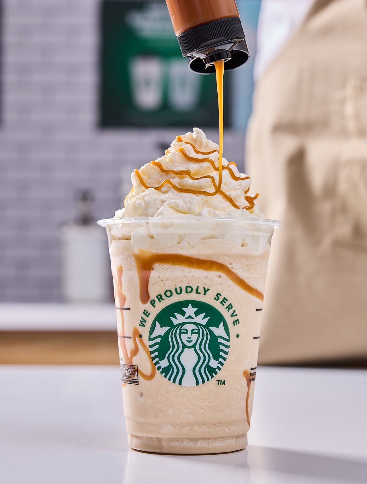 Une boisson frappée Starbucks nappée de crème fouettée, avec un filet de caramel ajouté par un barista.