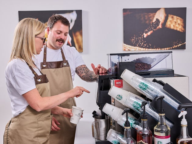 Deux baristas portant des tabliers, utilisant une machine à café approuvée par Starbucks 