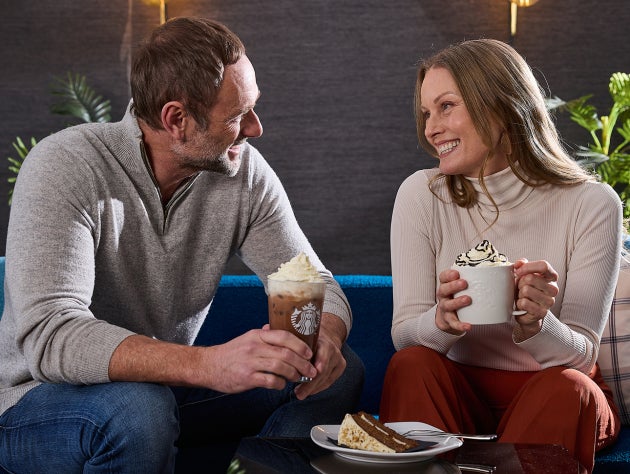 Deux professionnels de santé en blouse bleue tenant des boissons Starbucks au comptoir