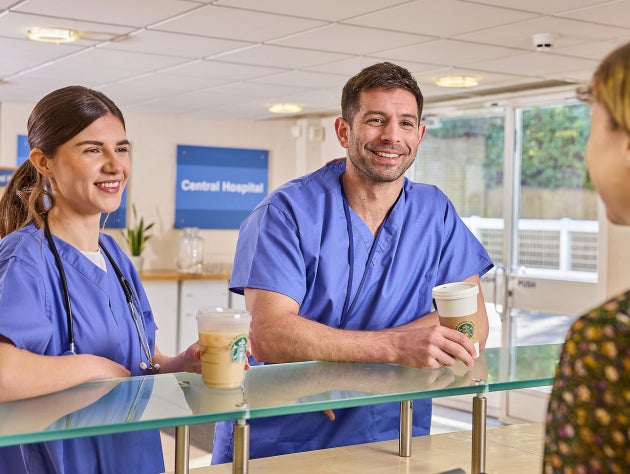 Deux professionnels de santé en blouse bleue tenant des boissons Starbucks au comptoir