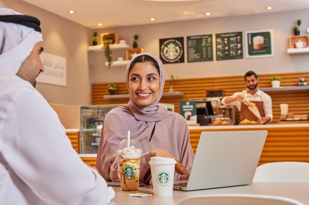 Un homme et une femme se regardent en souriant dans un café tout en savourant un café Starbucks