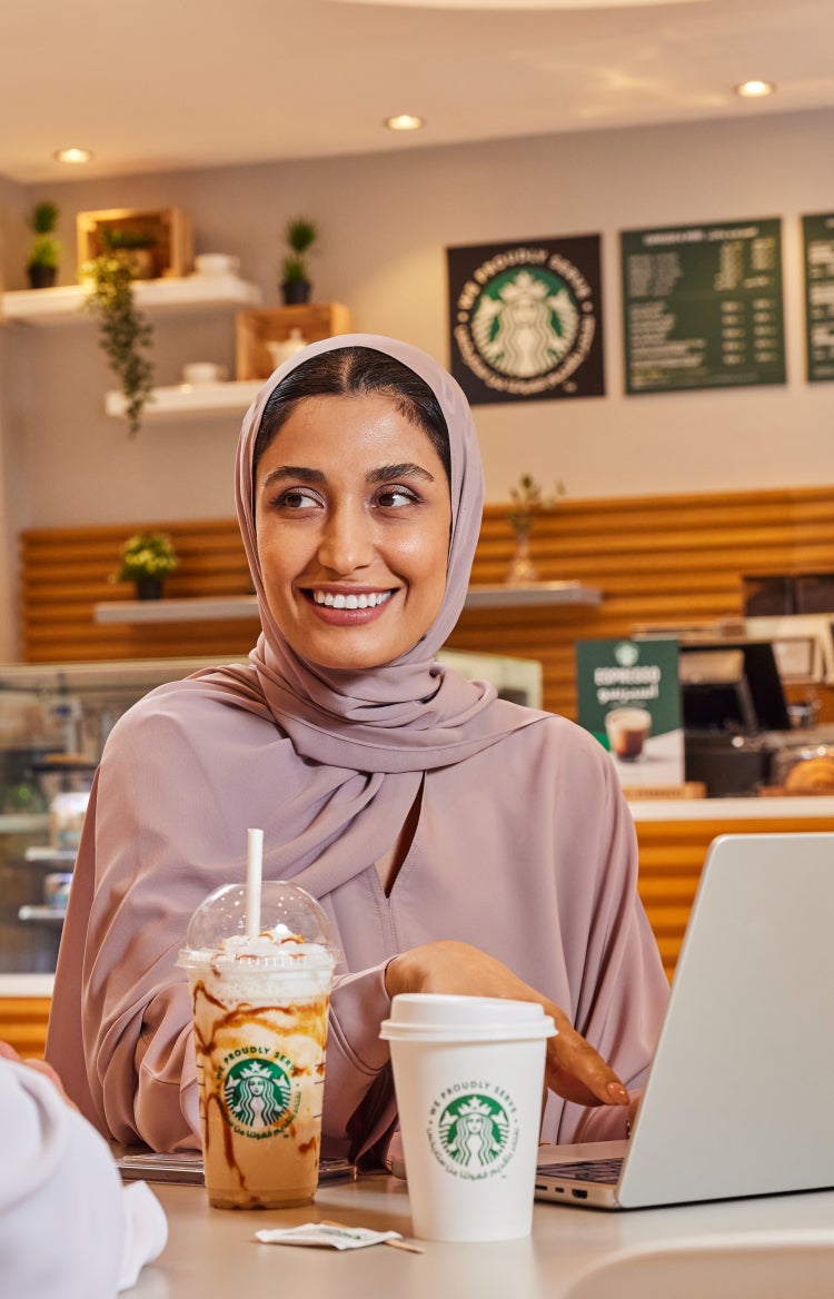 Un homme et une femme se regardent en souriant dans un café tout en savourant un café Starbucks